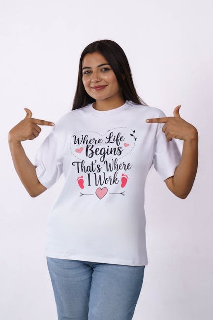 A young woman poses in a white T-shirt with a motivational print, pointing at the text.